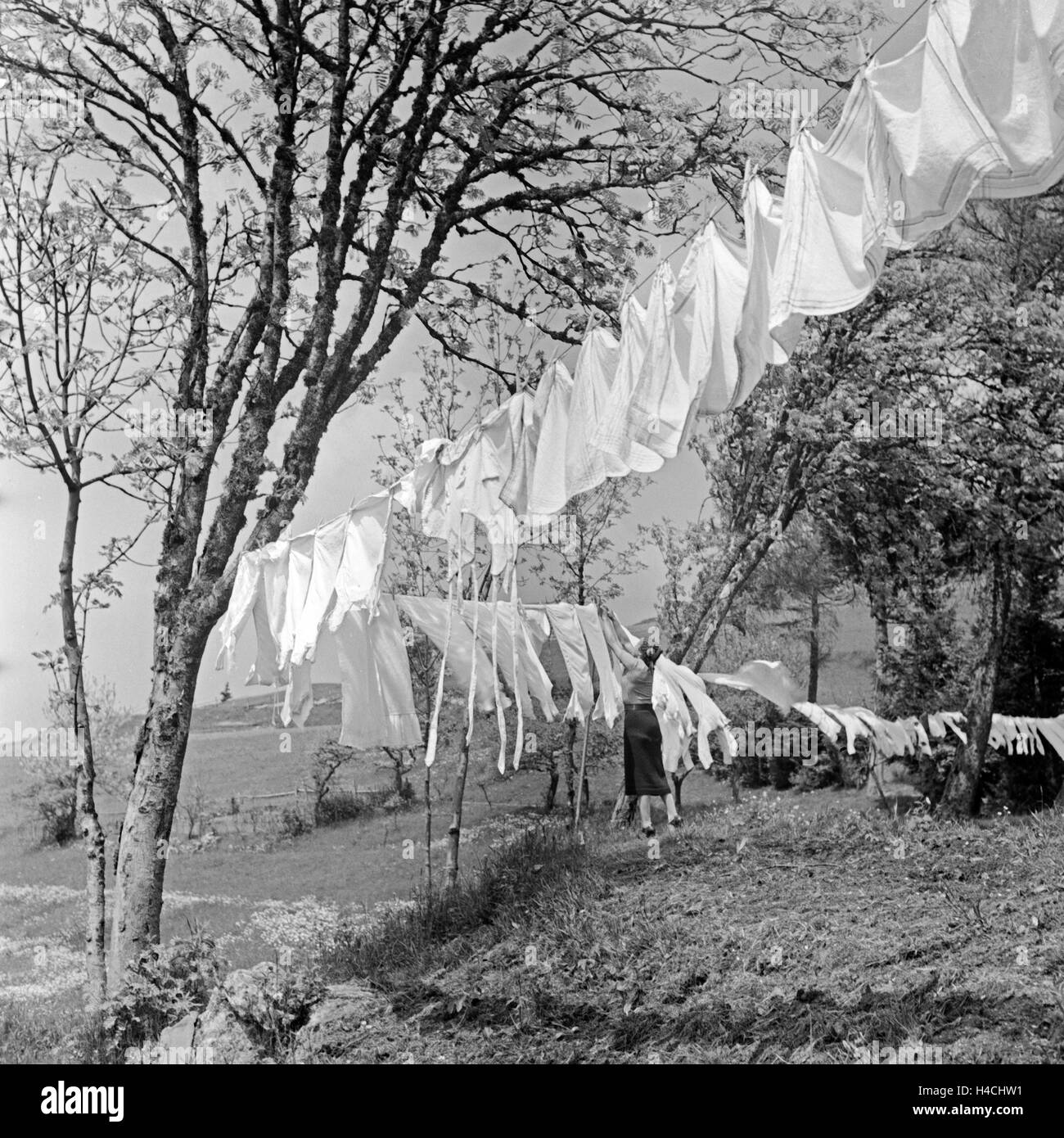 Eine Hausfrau hängt die frisch gewaschene Wäsche zum Trocknen auf die Leine im Schwarzwald, Deutschland 1930er Jahre. A housewife is hanging up the fresh washing at Black Forest, Germany 1930s. Stock Photo