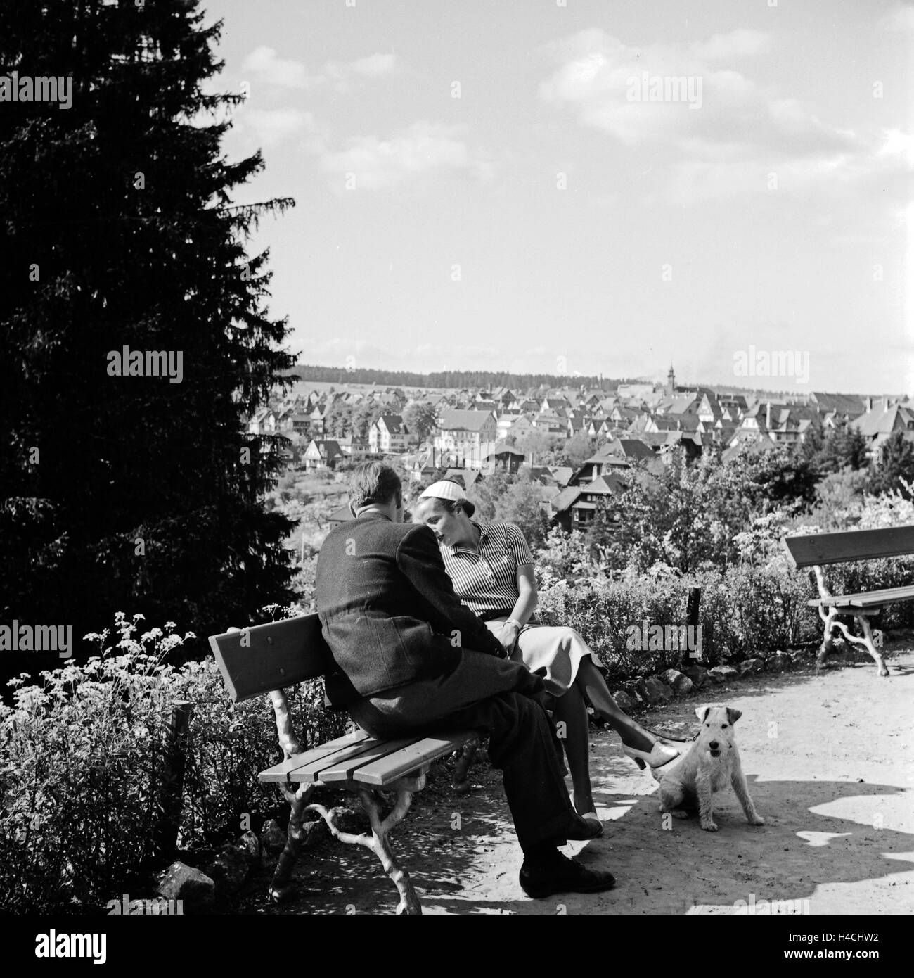 Ein Paar sitzt auf einer Anhöhe über Freudenstadt im Schwarzwald, Deutschland 1930er Jahre. A couple sitting on a bench over the city of Freudenstadt in Black Forest, Germany 1930s. Stock Photo