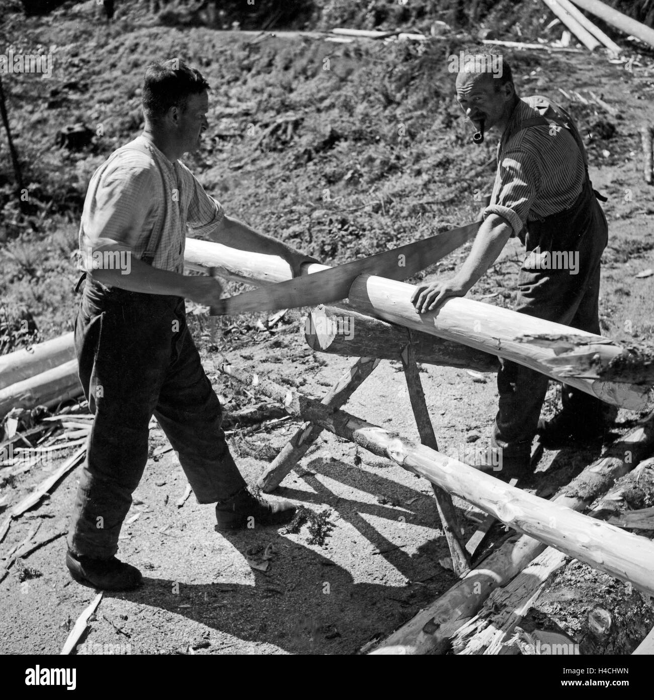 Holzfäller bei ihrer Arbeit an Baumstämmen im Schwarzwald, Deutschland 1930er Jahre. Woodcutters doing their job at wood trunks at Black Forest, Germany 1930s. Stock Photo
