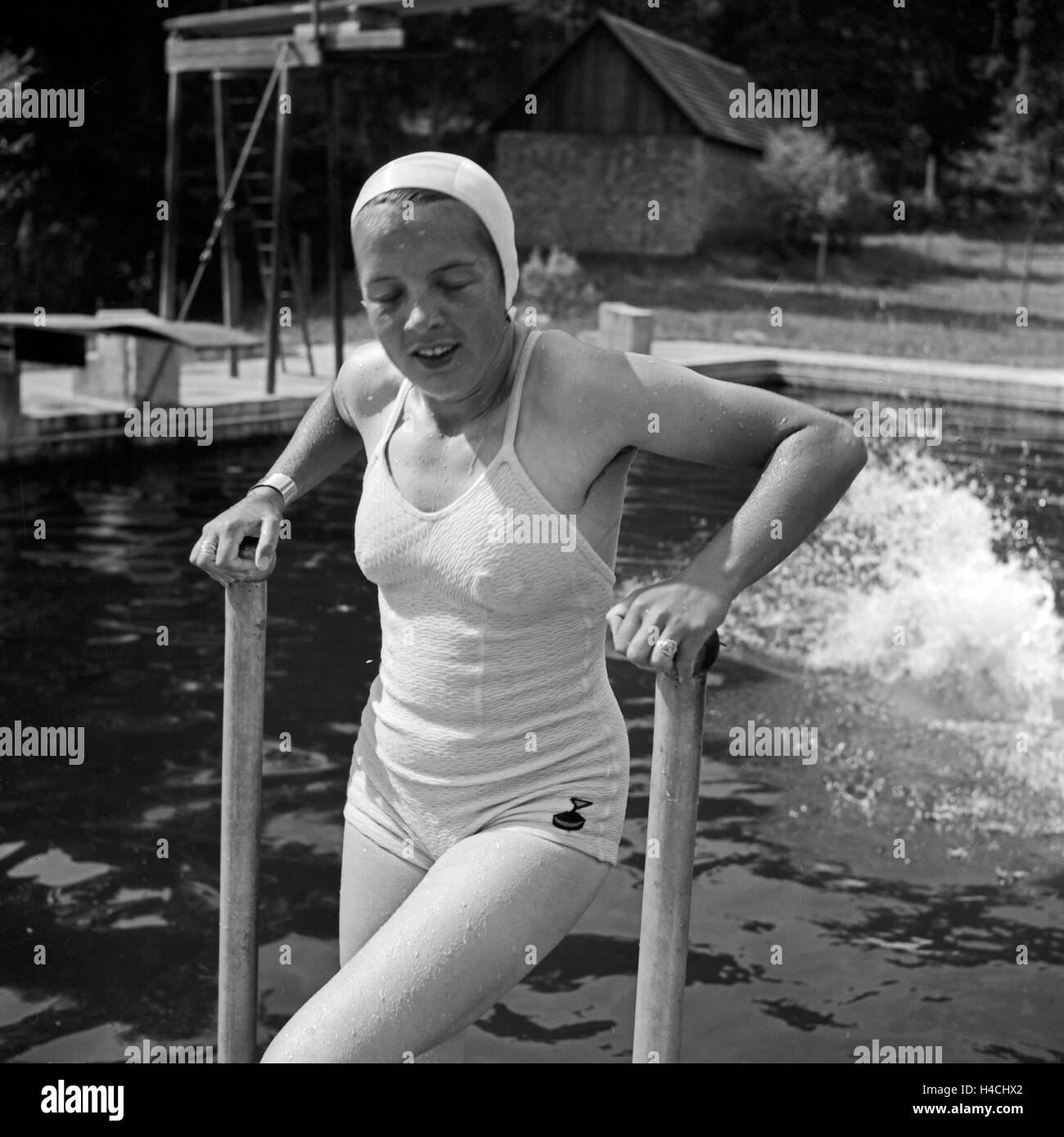 Eine junge Frau kommt nach einem Sprung ins Wasser wieder aus dem Becken, Deutschland 1930er Jahre. After a jumo in the pool a woman climbing out of the water, Germany 1930s. Stock Photo