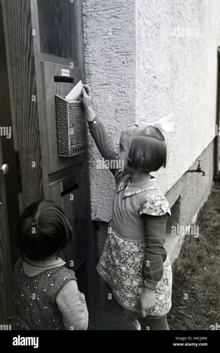 Zwei kleine Mädchen werfen einen Brief in den Briefkasten eines  Hauseingangs, Zeppelinsiedlung bei Frankfurt am Main, Deutschland 1930er  Jahre. Two little girls are posting a letter inside the letterbox next to a