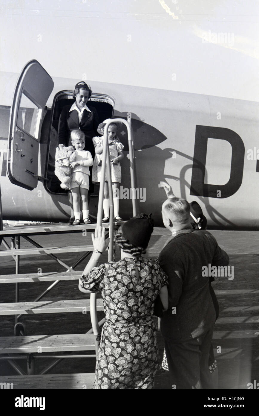 Stewardess hilft Kindern bei der Ankunft / Verabschiedung / beim Einstieg / Austieg aus dem Flugzeug, Deutschland 1930er Jahre. Stewardess helping children arriving / departing / entering / leaving a plane, Germany 1930s Stock Photo
