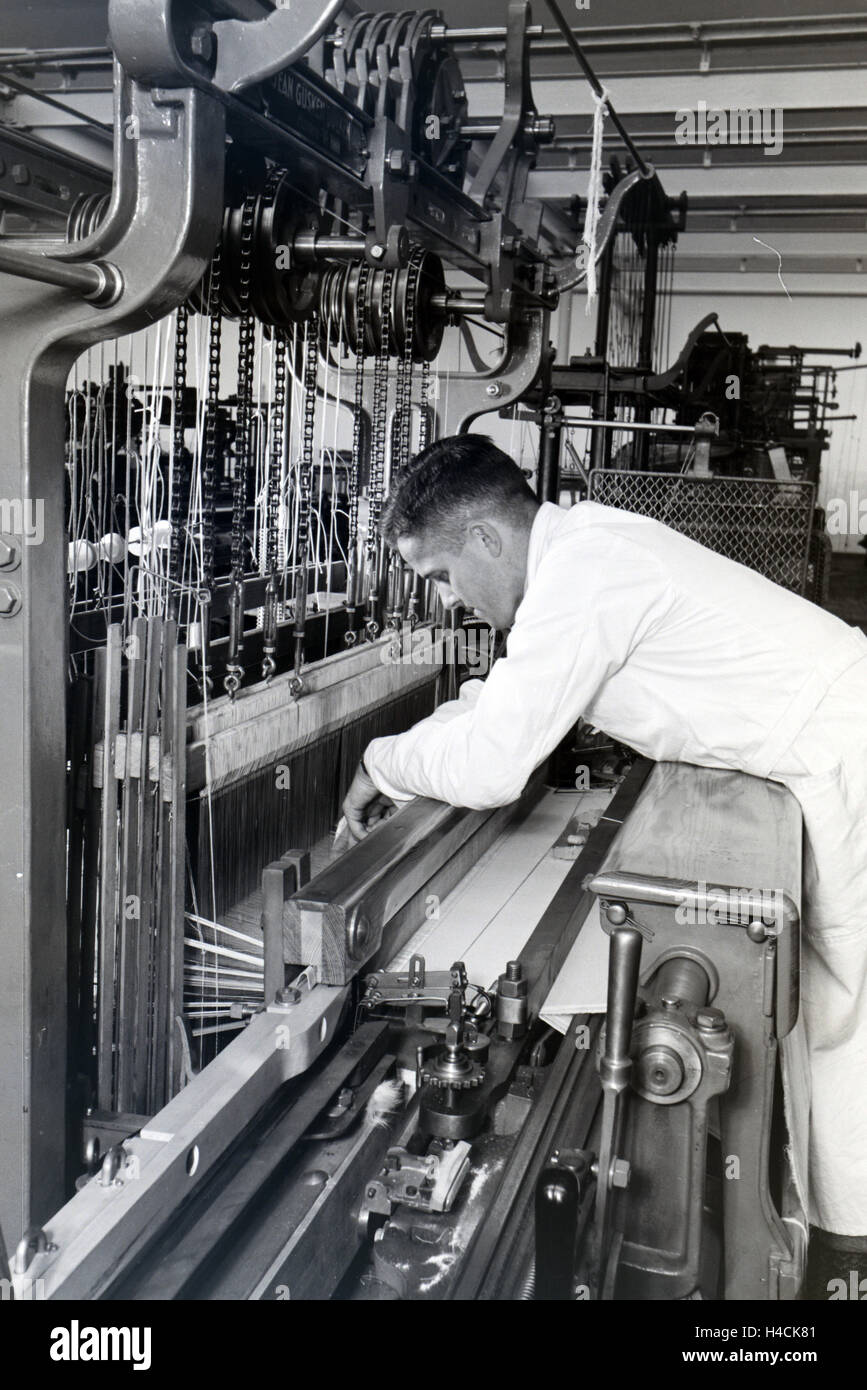 Ein Angestellter einer Textilfirma in Krefeld justiert das Garn in der großen Webmaschine, Deutschland 1930er Jahre. An employee in a textile company in Krefeld adjusting the yarn in the big power loom, Germany 1930s Stock Photo