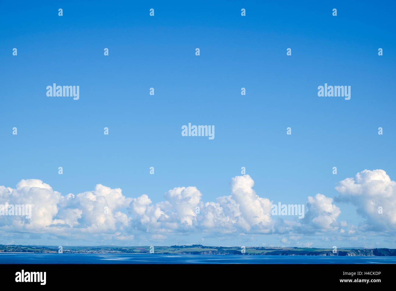 Weather - Cumulus clouds forming in a clear blue sky over a coastline - England, UK Stock Photo