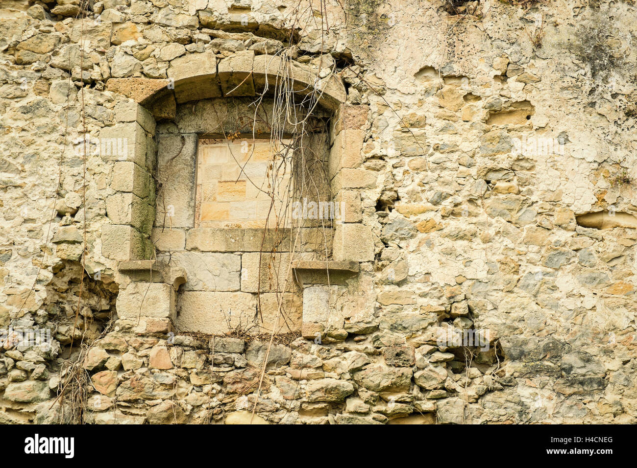 Crumbling exterior wall with window of an old stone house Stock Photo