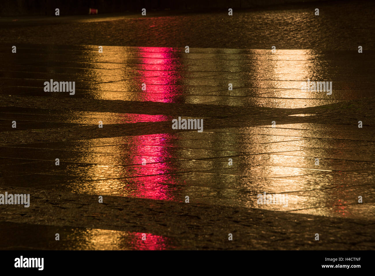 golden an red stripes on wet pavement by traffic reflection in the ...