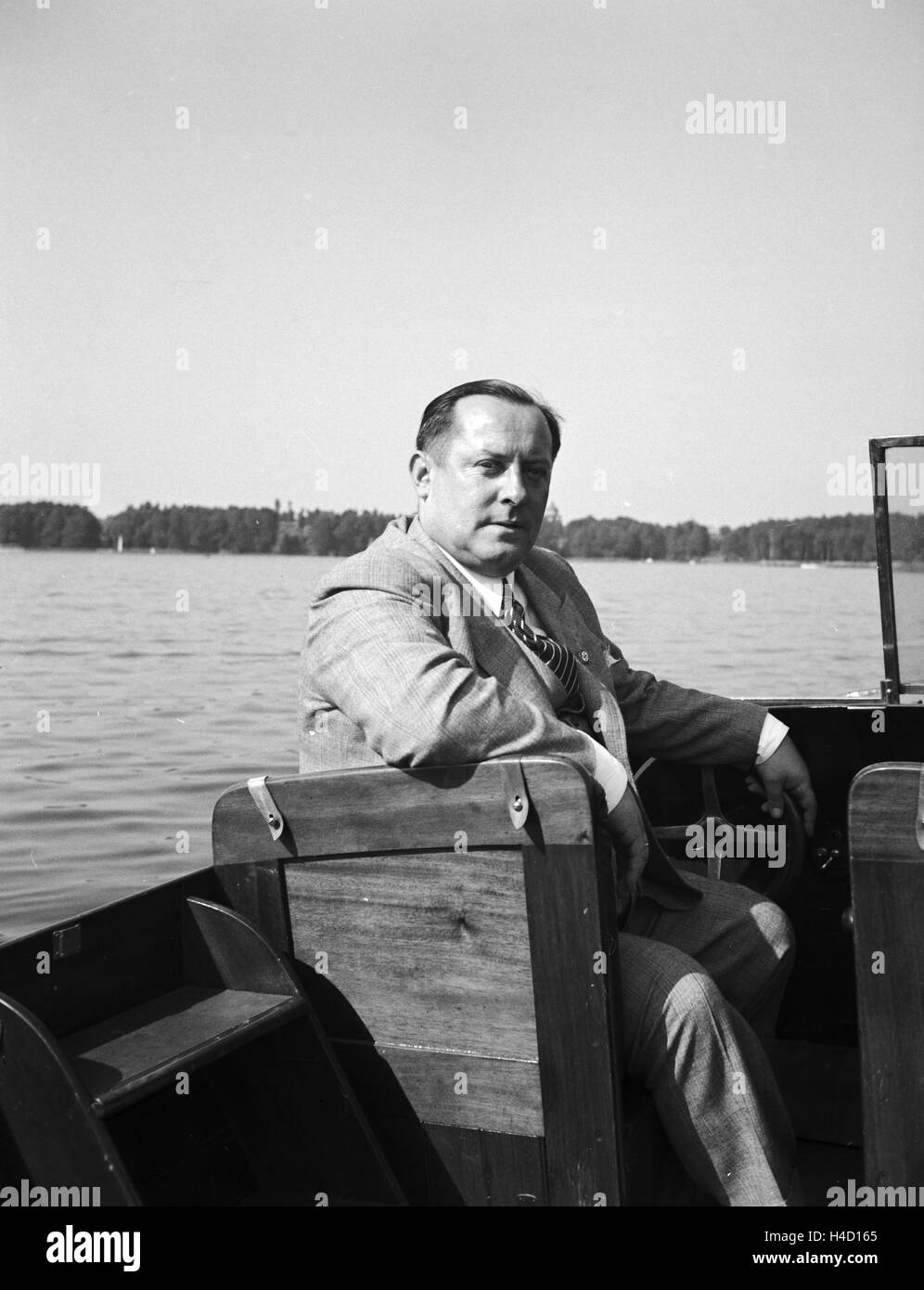 Ein Mann unterwegs in seinem Motorboot auf einem See, Deutschland 1930er Jahre. A man on a lake in his motor boar, Germany 1930s. Stock Photo