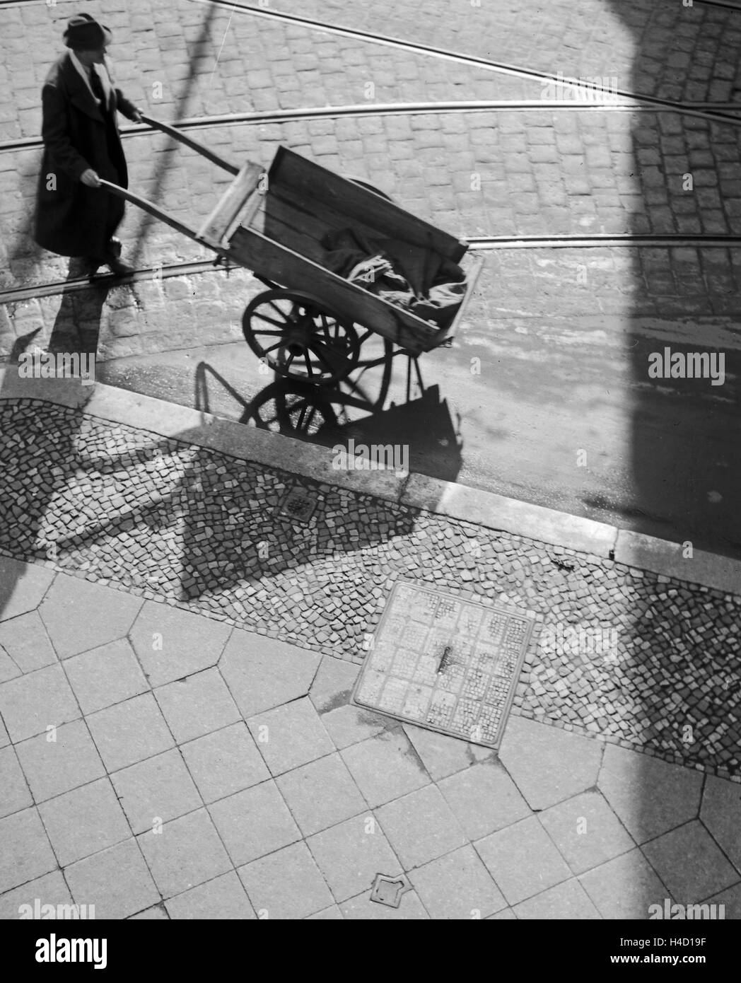 Ein Mann mit einem Handkarren in den Straßen von Berlin, Deutschland 1930er Jahre. A man with a push cart in the streets of Berlin, Germany 1930s. Stock Photo