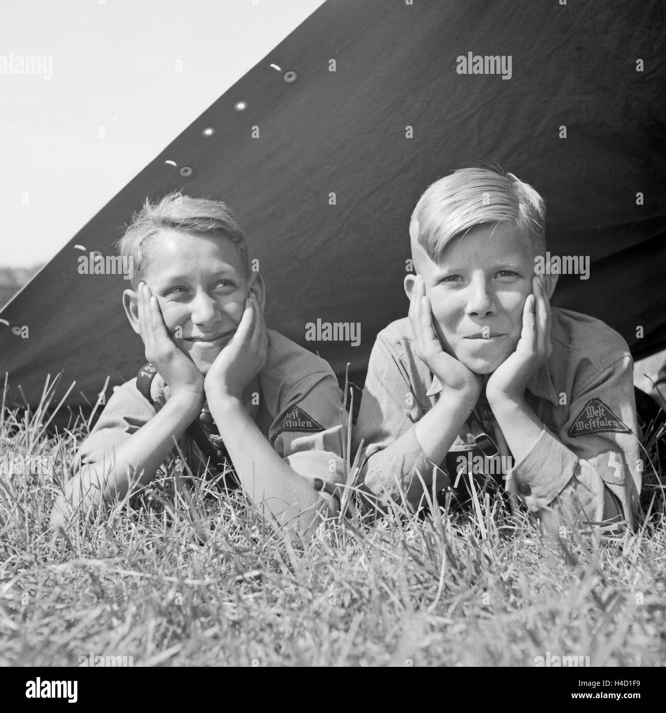 Zwei Hitlerjungen vom Gau Westfalen liegen in ihrem Zelt und schauen zufrieden heraus, Deutschland 1930er Jahre. Two Hitle youths watching happily out of their tent, Germany 1930s. Stock Photo