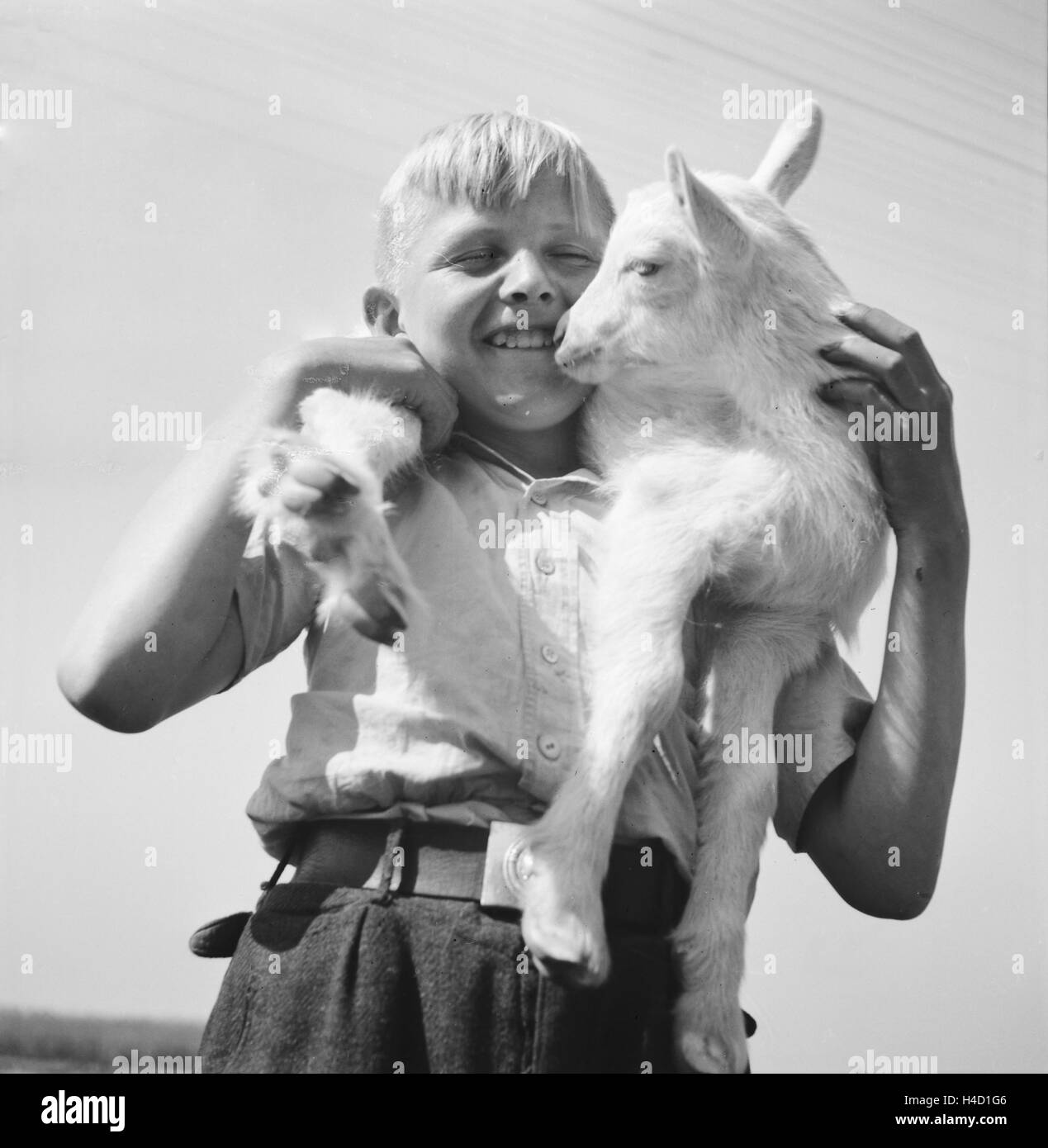 Kinder spielen mit einem Lamm, Deutschland 1930er Jahre. Children playing with a little lamb, Germany 1930s. Stock Photo