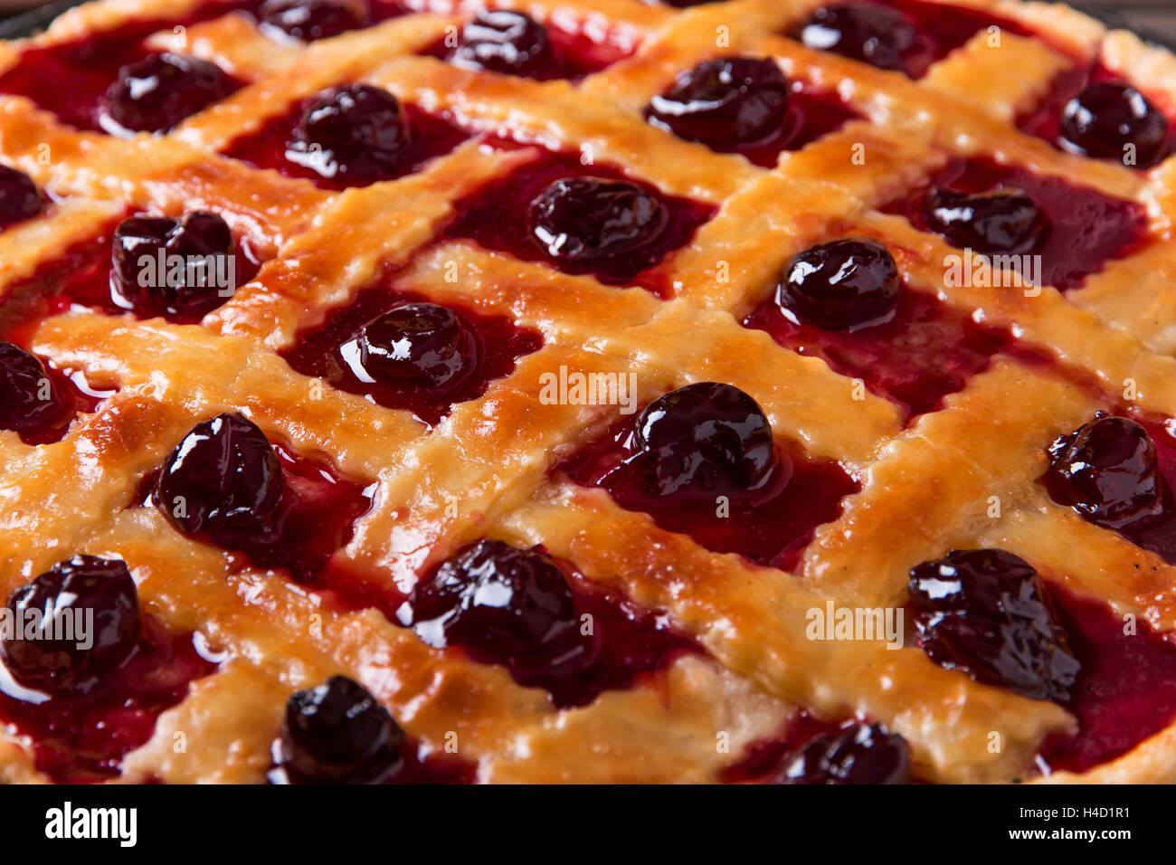 Homemade traditional sweet cherry tart pie with wooden table background