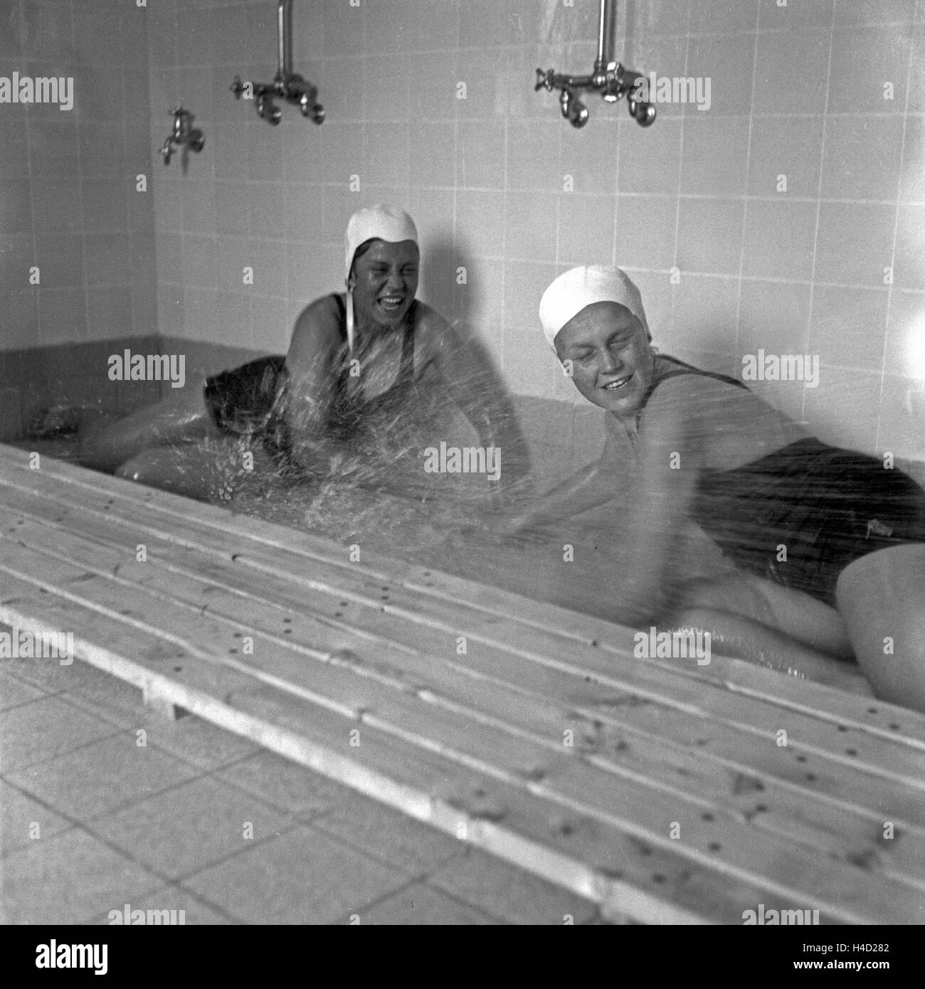 Zwei BdM Mädchen liefern sich eine Wasserschlacht in der Dusche der Haushaltungsschule Greifenberg an einem Brunnen, Deutschland 1930er Jahre. BdM girls having fun at the shower at the domestic science school at Greifenberg, Germany 1930s. Stock Photo