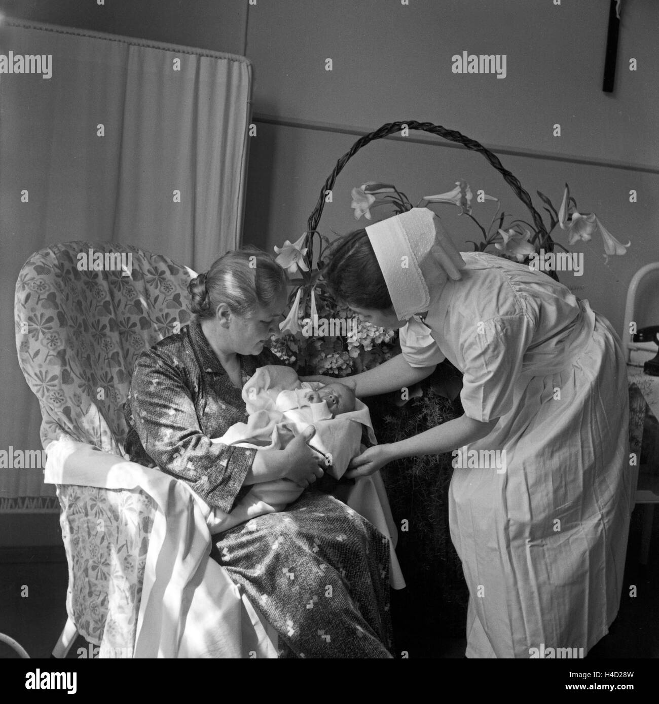 Neuankömmling auf der Geburtsstation des Rotkreuzkrankenhauses München, Deutschland 1930er Jahre. New born baby with grandmother and nurse at the neonatal ward of the Red Cross hospital at Munich, Germany 1930s. Stock Photo