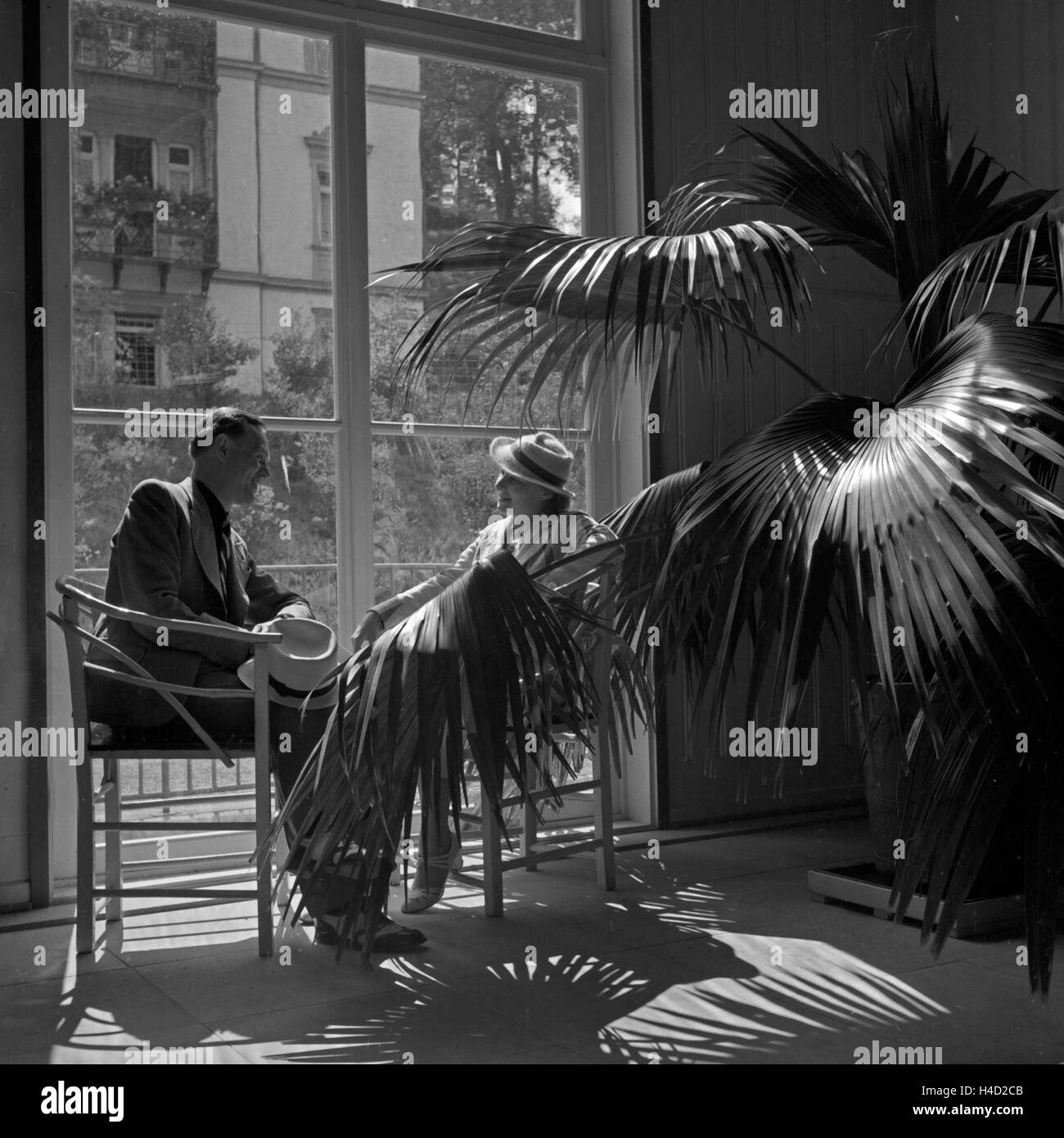 Ein Mann und eine Frau sitzen an einem Fenster einer Hotellobby in Wildbad im Schwarzwald, Deutschland 1930er Jahre. A man and a woman sitting by a window of a hotel lobby at Wildbad in Black Forest, Germany 1930s. Stock Photo