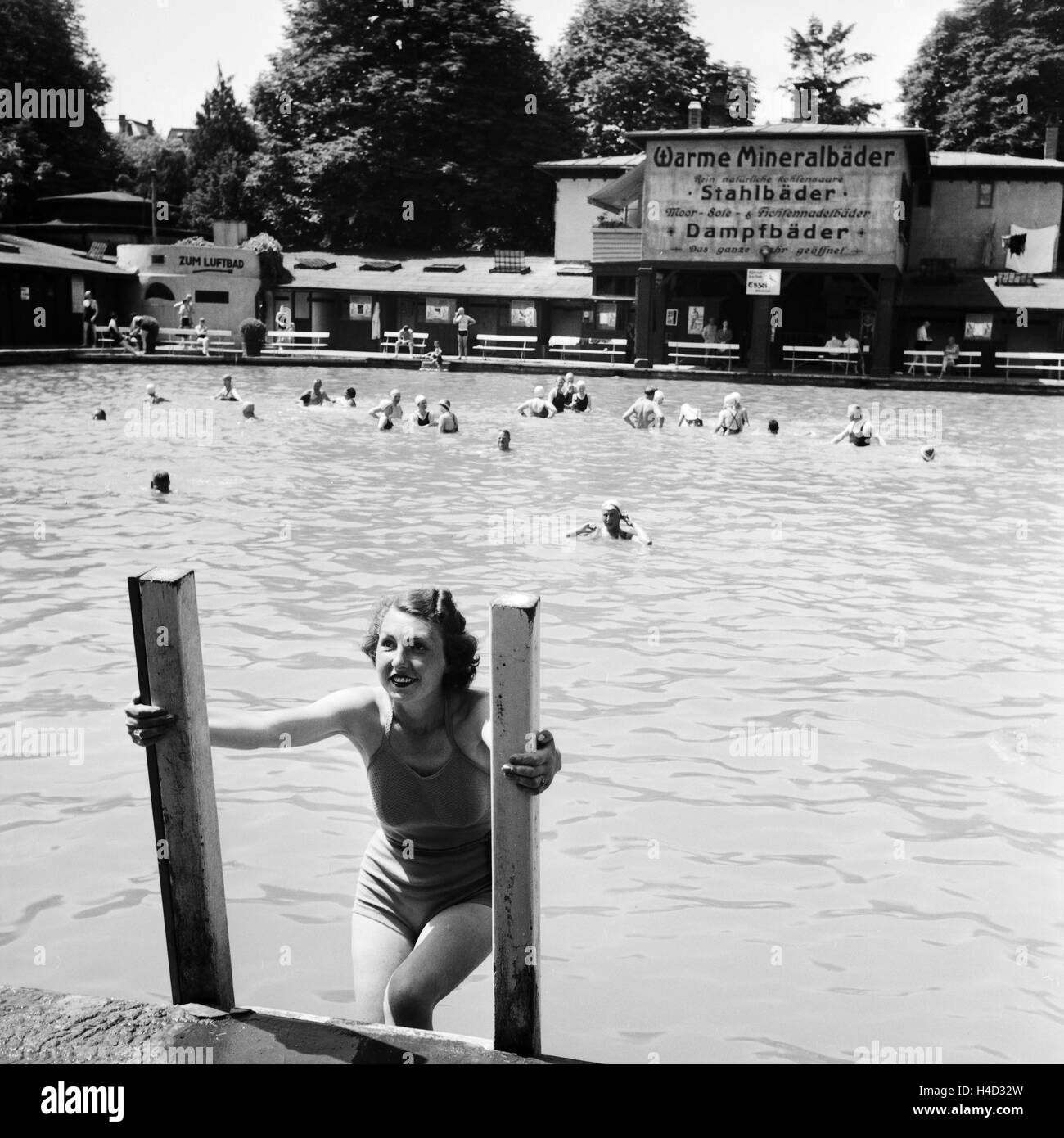 Eine Frau steigt aus dem Schwimmbecken eines Mineralbads, Deutschland 1930er Jahre. A woman climbing off of a spa swimming pool, Germany 1930s. Stock Photo