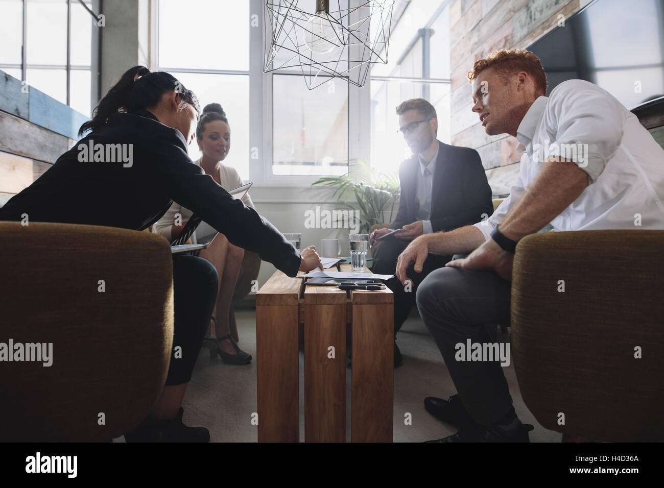Business colleague sitting at table during corporate meeting. Businessmen and businesswomen discussing new project in office lob Stock Photo
