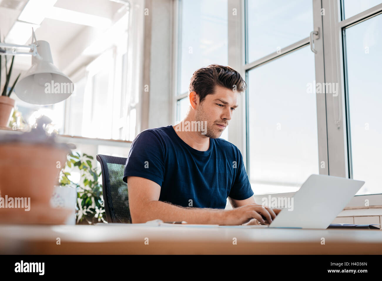 Young male executive working on laptop at his desk. Young businessman using laptop computer at work. Stock Photo