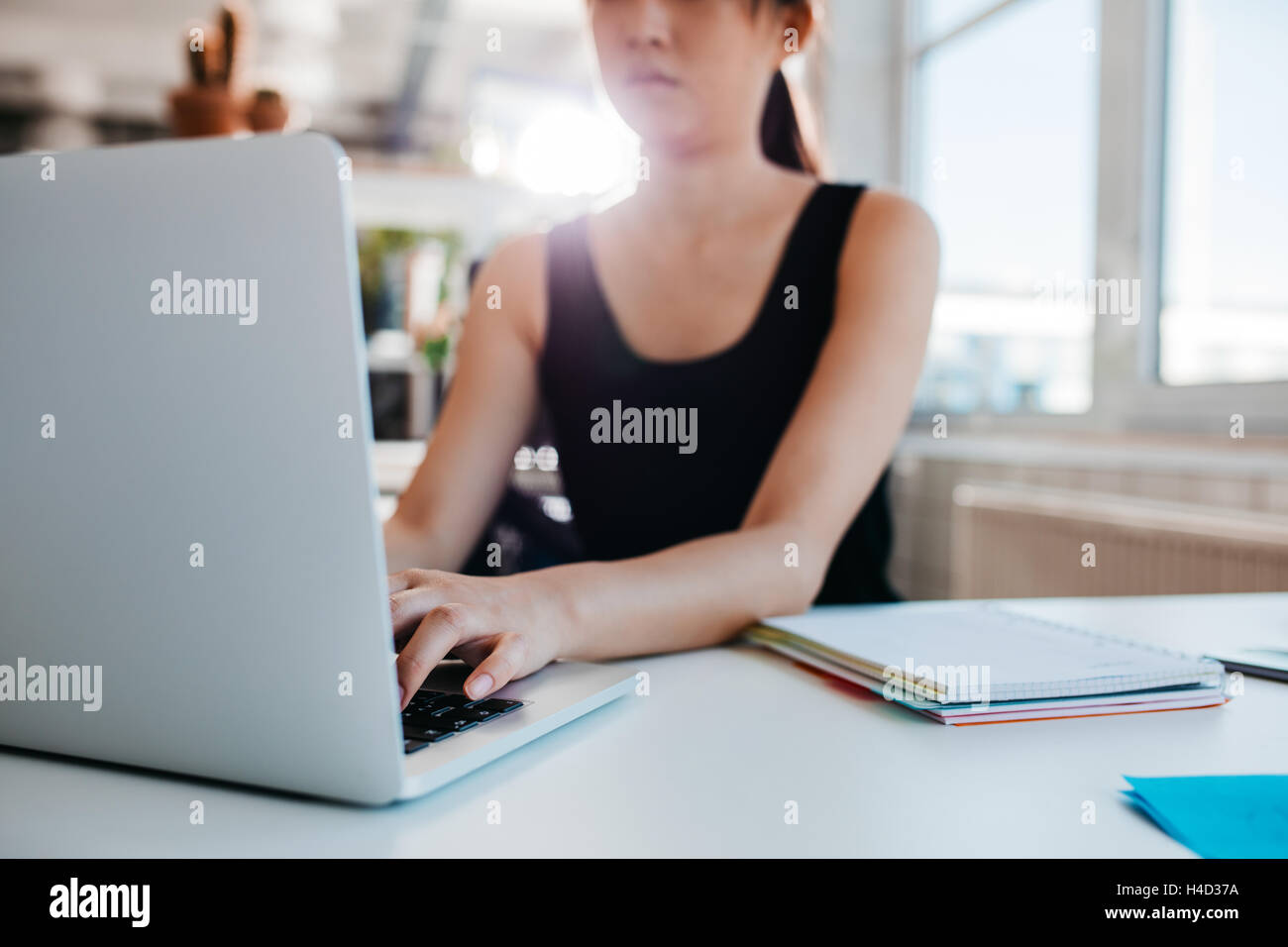 Cropped shot of woman working on laptop at office. Focus on hands of female typing on laptop keyboard. Stock Photo