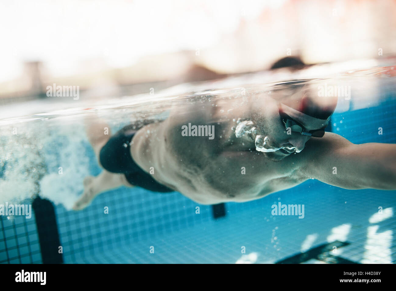 Underwater shot of male athlete swimming in pool. Young man swimming the front crawl in a pool. Stock Photo