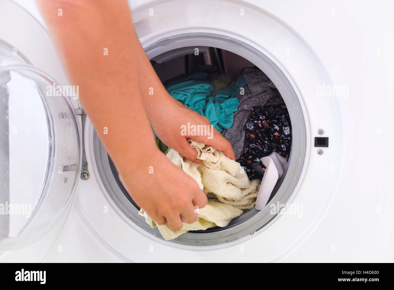 Woman picking up clothes out of the washing machine. Close up Stock