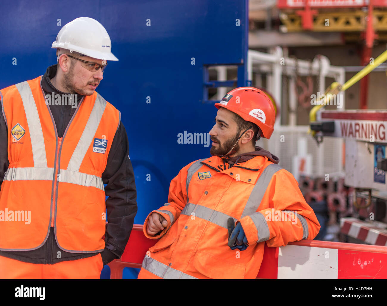 Two builders on site in orange safety clothing and hard hats Stock Photo