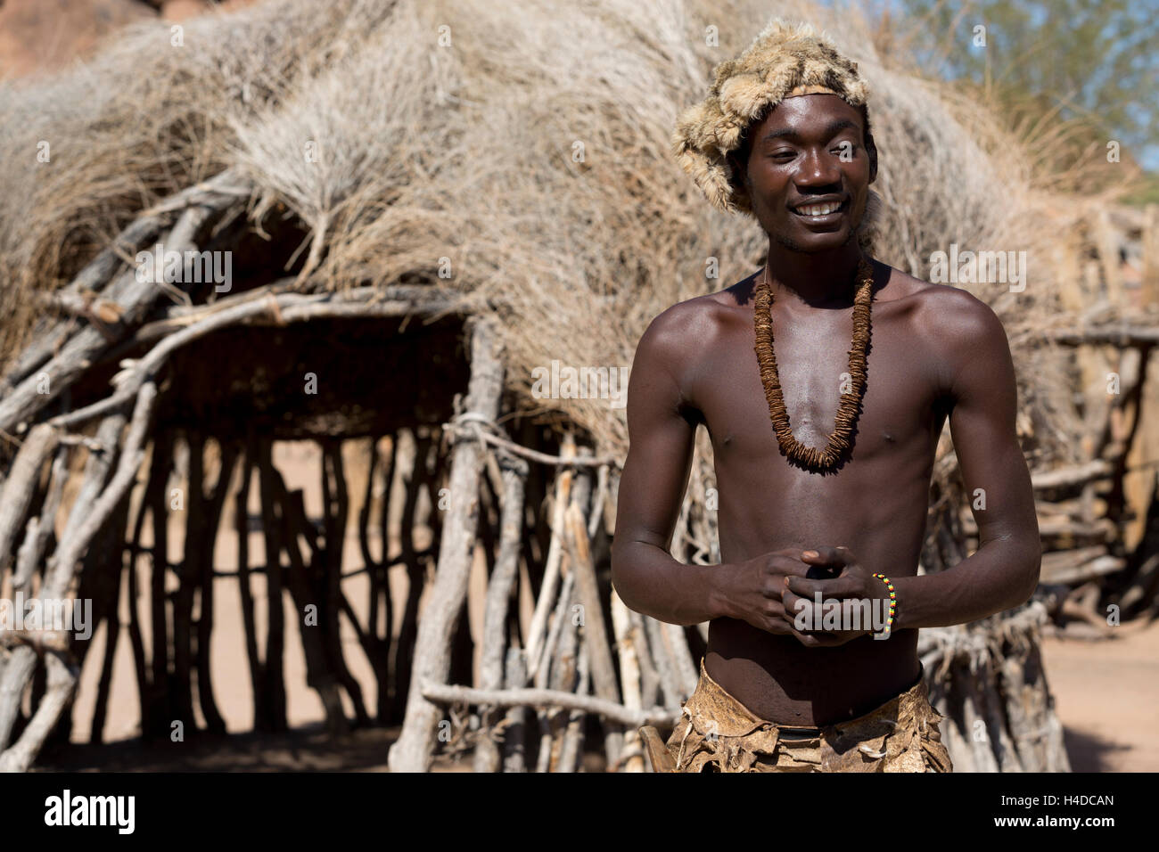 African hunter from Damara people stays near the hut in the village in