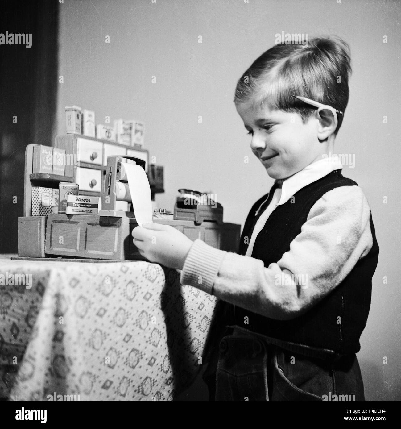 Ein kleiner Junge spielt mit seinem Kaufladen, Deutschland 1930er Jahre. A little boy playing with his shoppe, Germany 1930s. Stock Photo