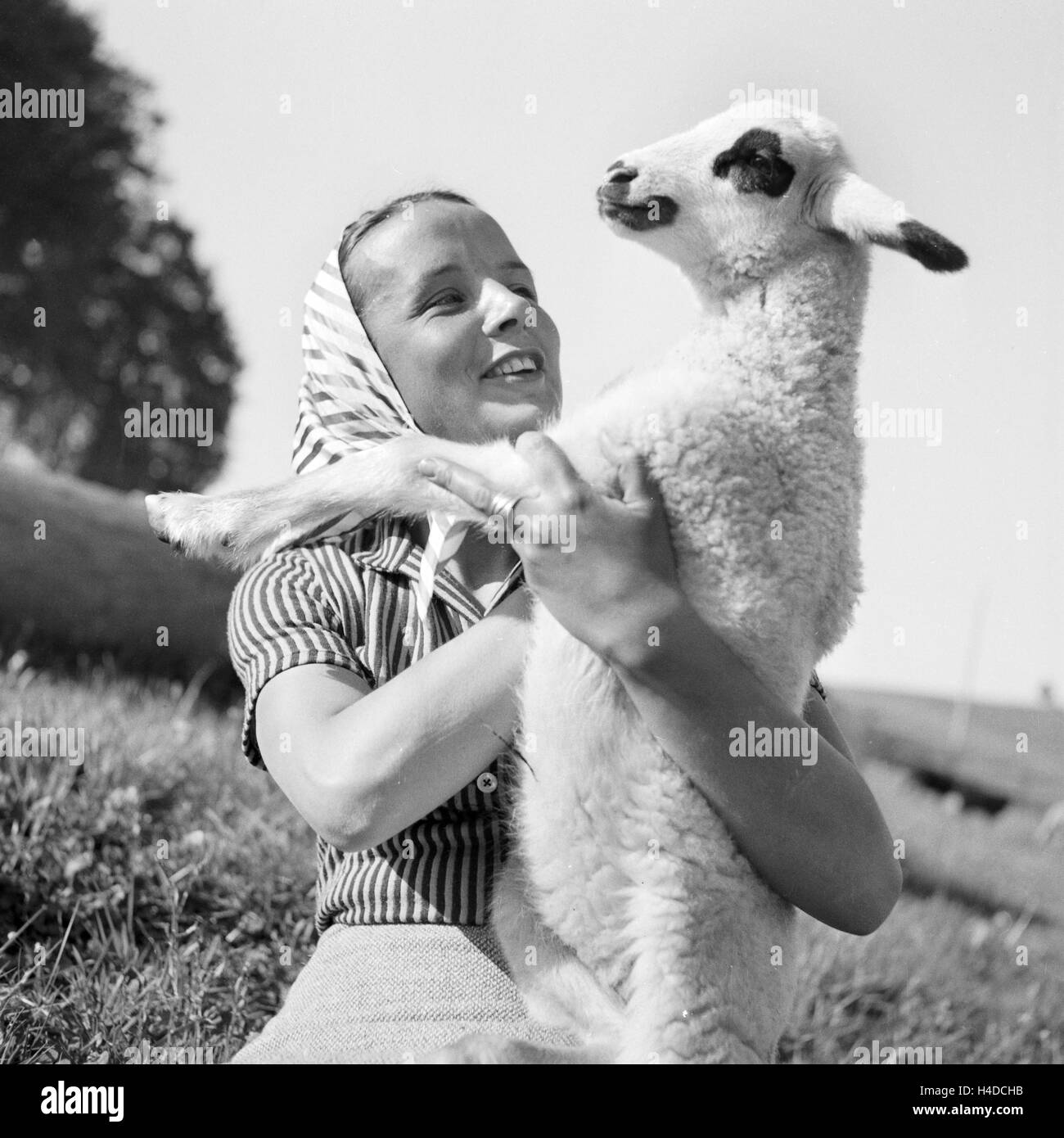 Junge Frau mit einem Lamm, Deutschland 1930er Jahre. Young woman holding a lamb, Germany 1930s. Stock Photo