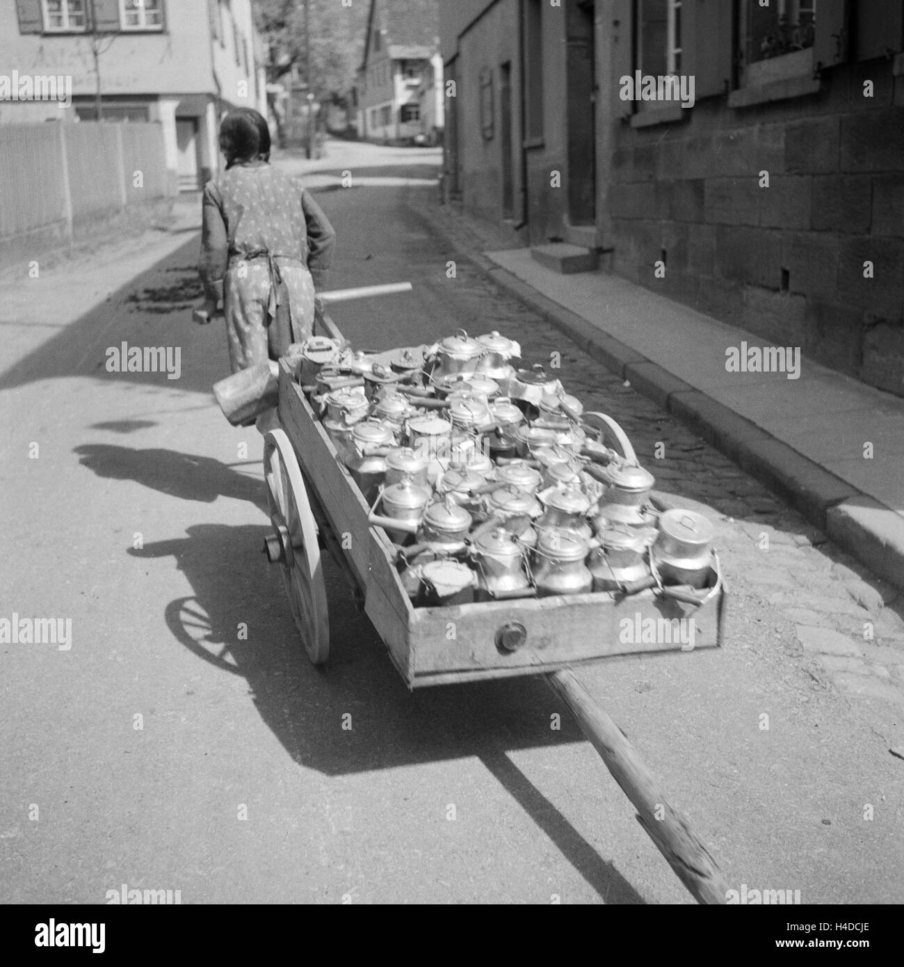 Mädchen zieht Handkarren mit Milchkannen, Deutschland 1930er Jahre. Girl pulling push cart with milk cans, Germany 1930s. Stock Photo
