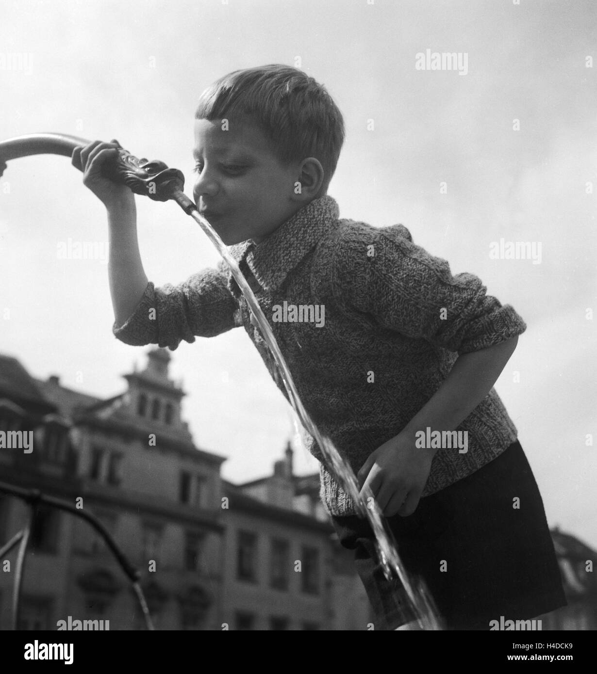 Ein Junge trinkt Wasser aus einem Brunnen, Deutschland 1930er Jahre. A boy drinking water from a fountain, Germany 1930s. Stock Photo