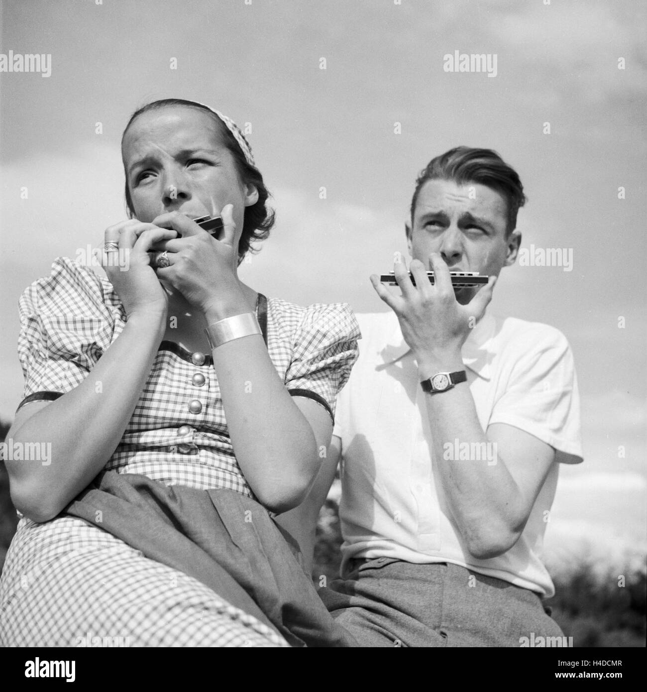 Ein Mann und eine Frau spielen Mundharmonika, Deutschland 1930er Jahre. A man nand a woman playing harmonica, Germany 1930s. Stock Photo