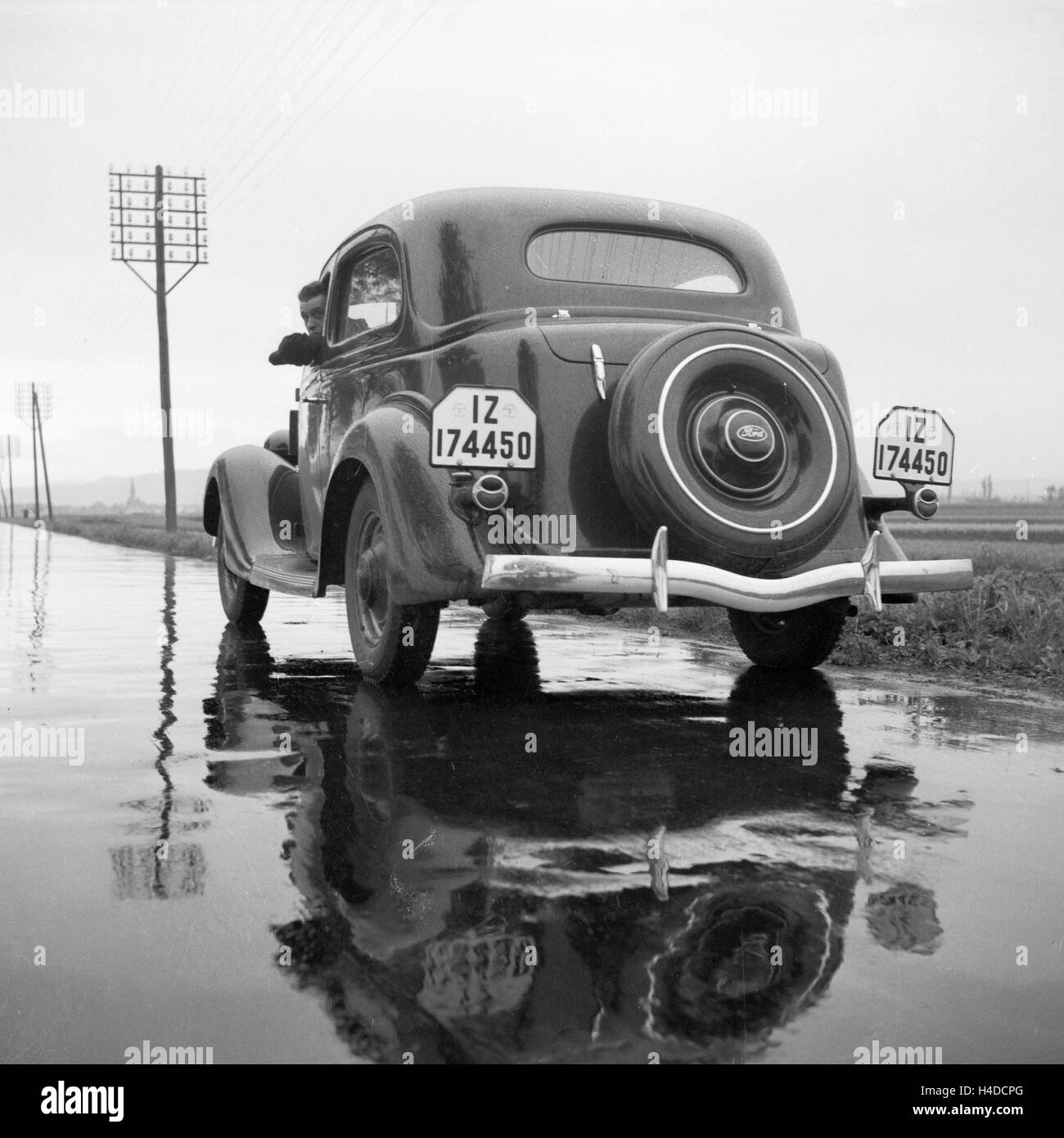 Mit dem Ford V8 auf regennasser Fahrbahn, Deutschland 1930er Jahre. With the Ford V8 on a wet street, Germany 1930s. Stock Photo
