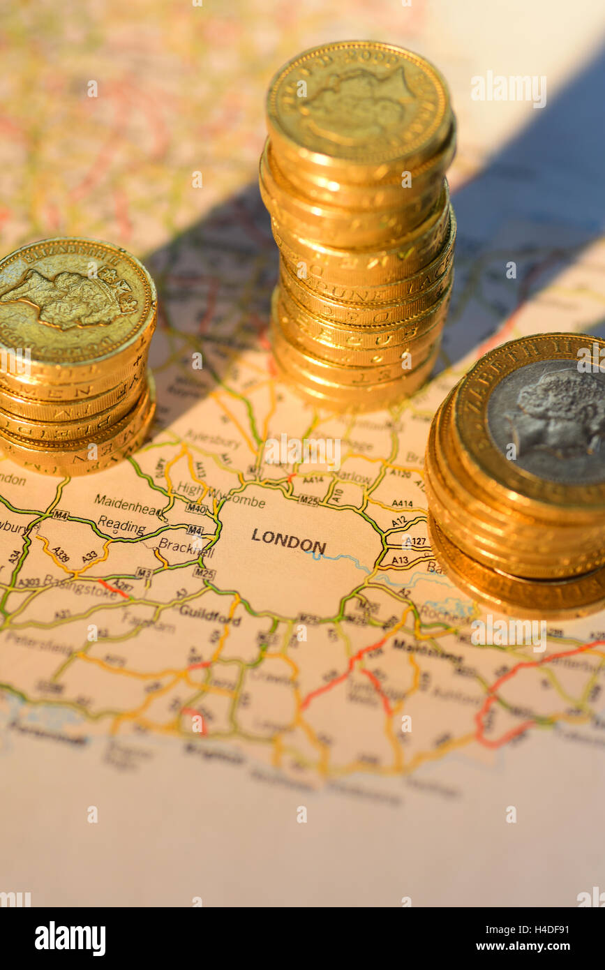 piles of one pound coins around road map showing london united kingdom Stock Photo