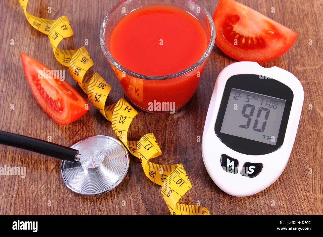 Glucose meter with good result sugar level, tape measure and fresh tomato with glass of tomato