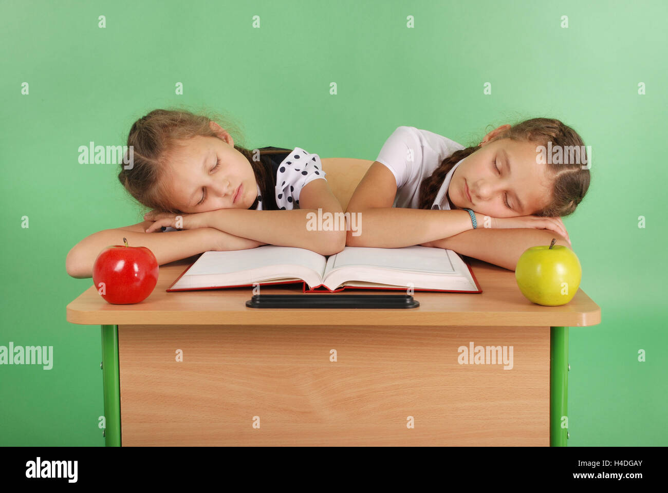 Two school girls sleeping on a stack of books at her desk isolated on ...