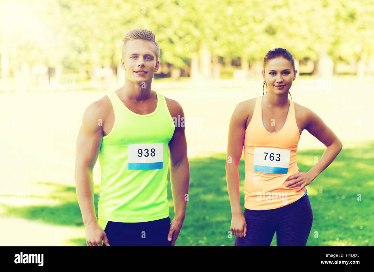 happy friends or couple with racing badge numbers Stock Photo - Alamy