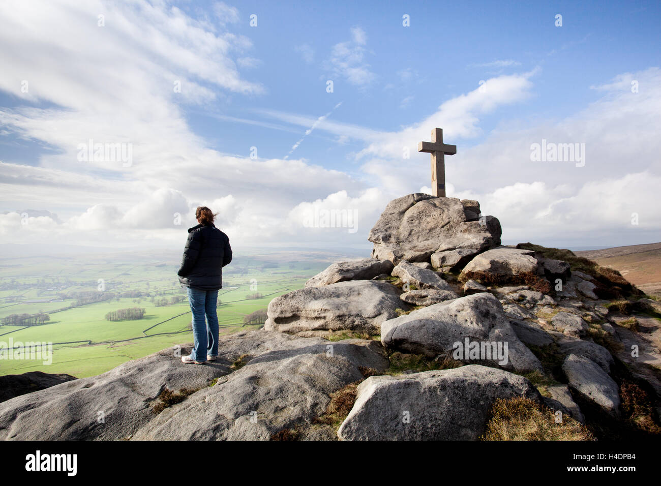 Woman at Rylstone Cross, crucifix overlooking the green pastures at the