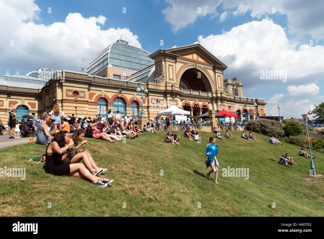 People sitting on grass outside Alexandra Palace during Alexandra Park Festival, Haringey, London, England, UK Stock Photo