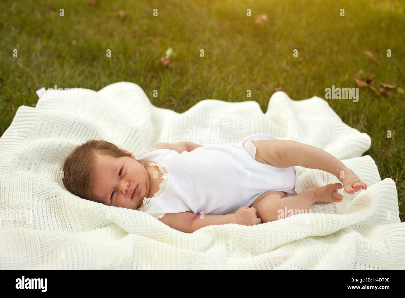 Baby lying on the blanket on the grass Stock Photo