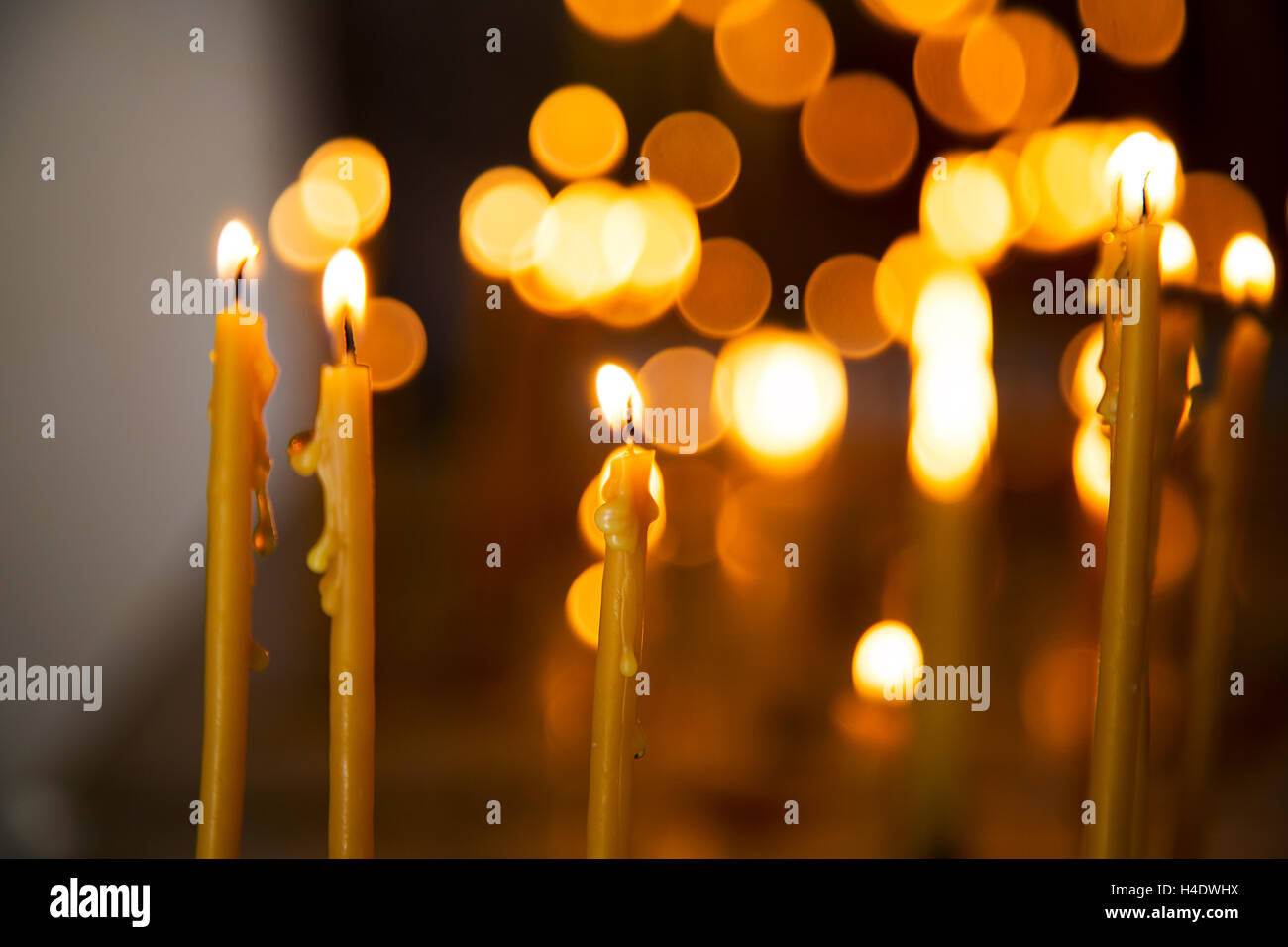 Candle in front of many defocused candleflames creating a spiritual atmosphere and in remembrance of loved ones Stock Photo