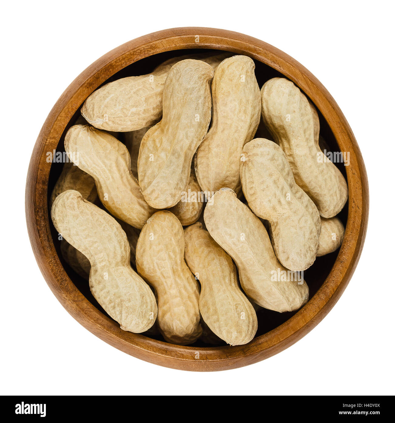 Peanuts with shell in wooden bowl over white, also called groundnut and goober. Dry roasted whole pods of Arachis hypogaea. Stock Photo