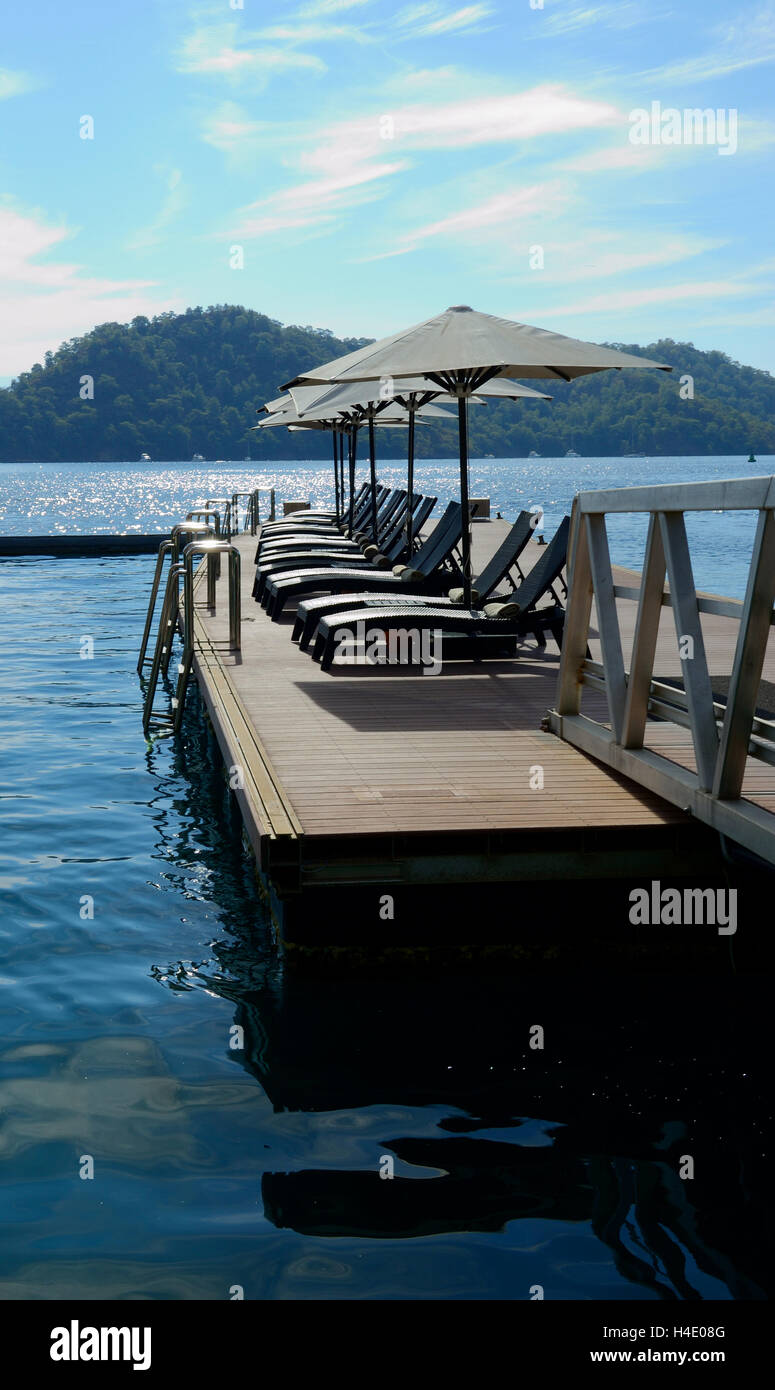 Deck with Umbrellas and lounge chairs on the ocean Stock Photo