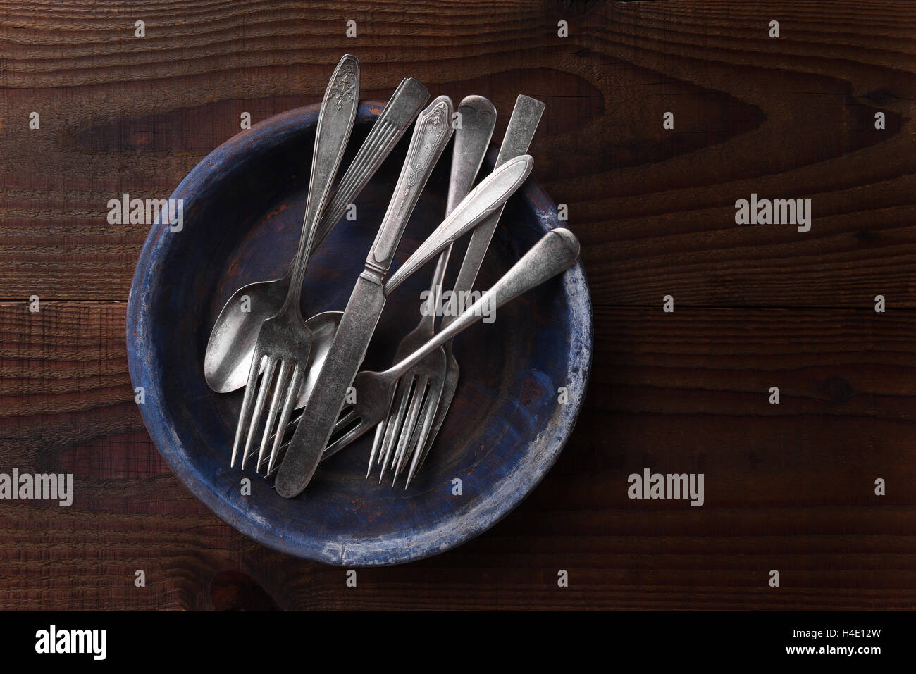 Top view of antique silverware on a plate on dark wood kitchen table. Stock Photo