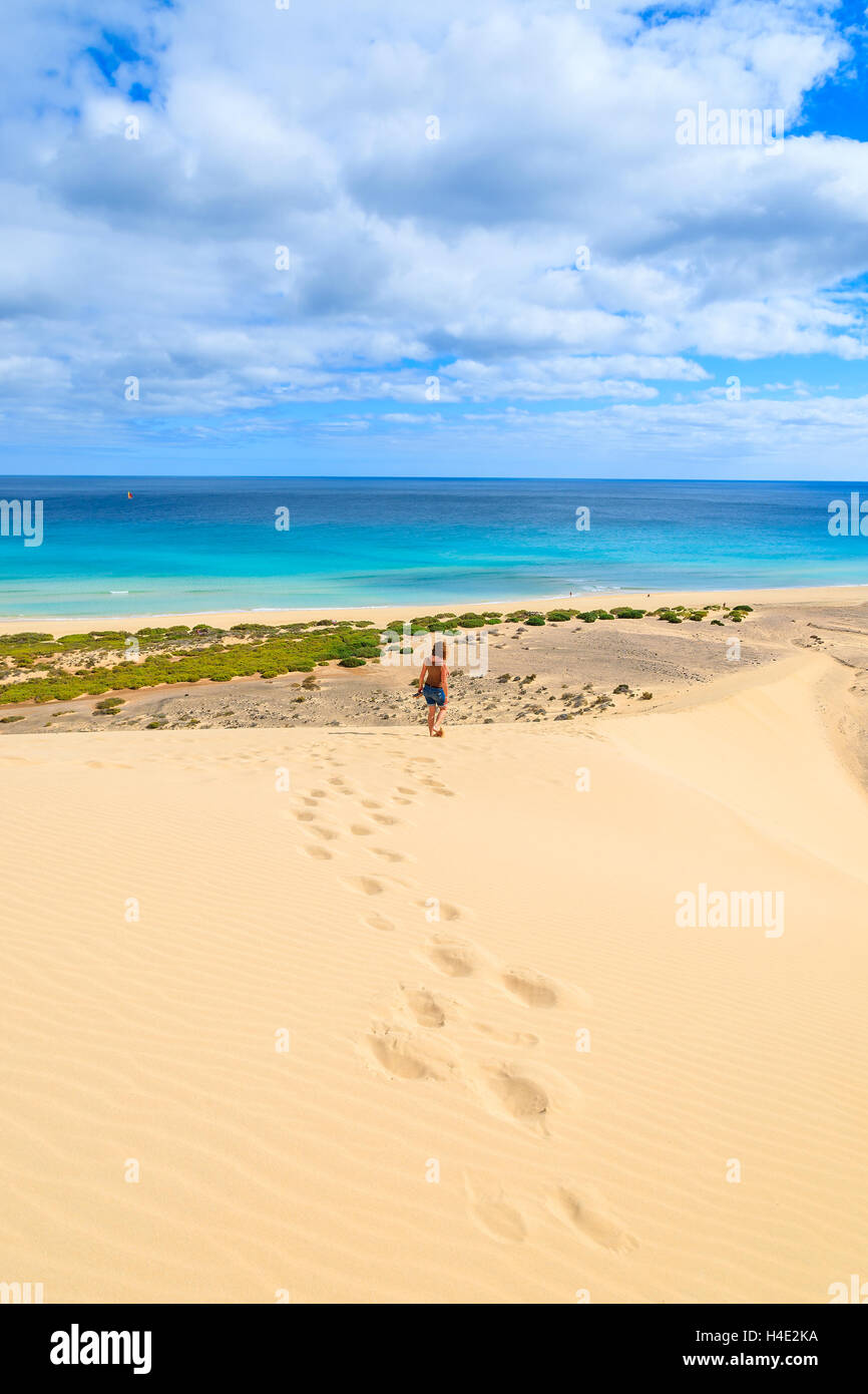 Footprints in sand with unidentified young woman walking down on a dune at Sotavento beach on Jandia peninsula, Fuerteventura, Canary Islands, Spain Stock Photo