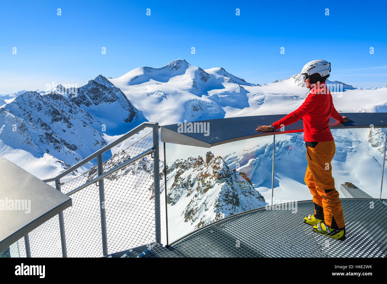PITZTAL SKI RESORT, AUSTRIA - MAR 29, 2014: Woman skier standing on platform looking at Wildspitze mountain, second highest peak in Austria. March is most sunny month for ski holidays. Stock Photo