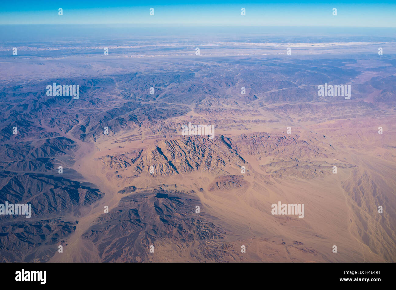 The yellow plain surrounded by the black rocks in Egyptian Sahara. Stock Photo