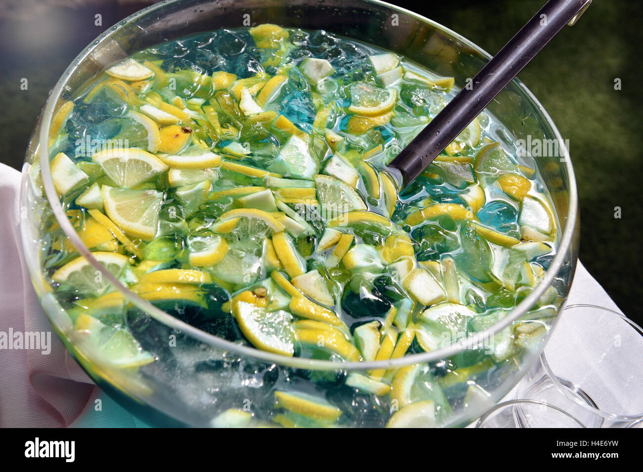 Sliced fresh lemon and ice in a refreshing bowl of summer beverage with a ladle for serving it viewed close up high angle Stock Photo