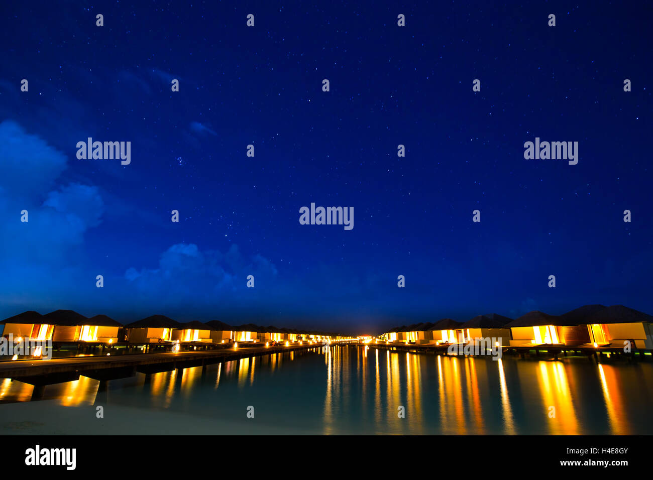 Overwater bungalows on the tropical island resort of Maldives at night with heaven full of stars. Stock Photo