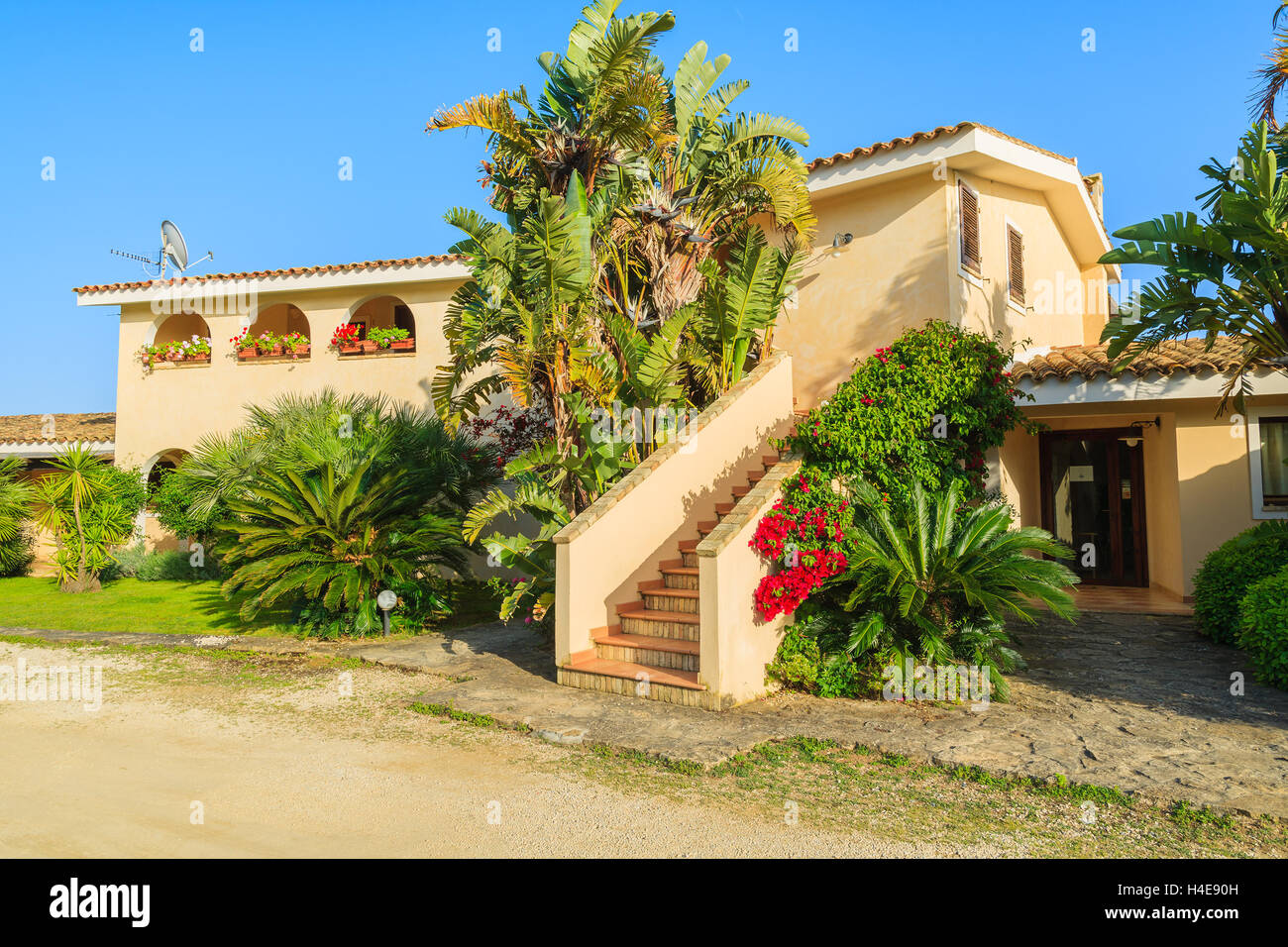 PORTO GIUNCO, SARDINIA - MAY 24, 2014: holiday apartment hotel in tropical gardens, Sardinia island, Italy. Southern part of the island is popular for beach vacation among Europeans. Stock Photo
