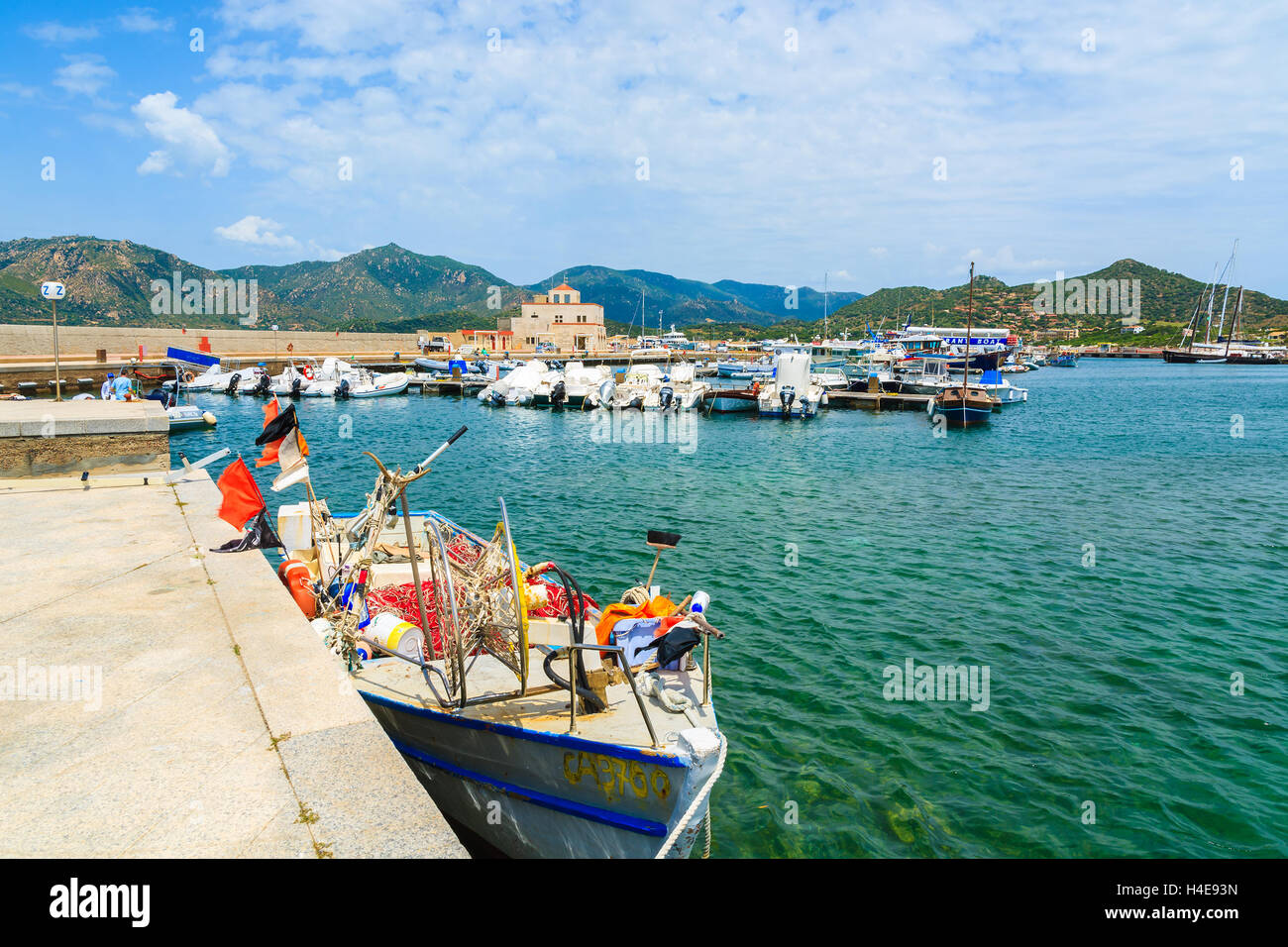 PORTO GIUNCO PORT, SARDINIA - MAY 25, 2014: fishing boat and net on shore in Porto Giunco touristic port, Sardinia island, Italy. Many tourists visit Sardinia island in summer time. Stock Photo